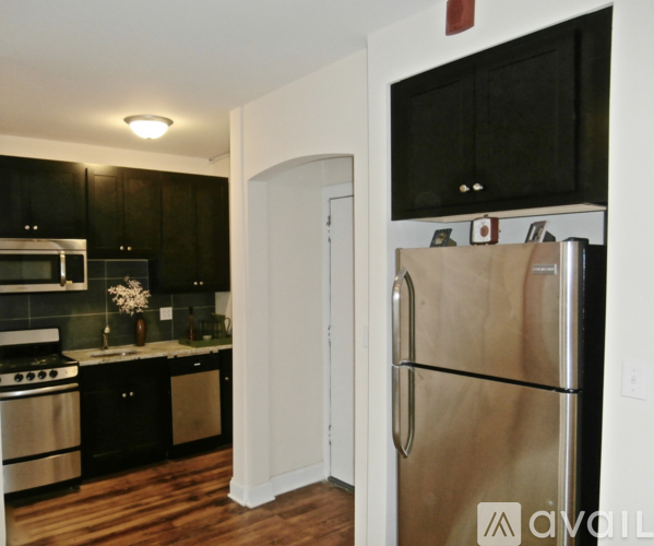 A kitchen with black cabinets and a stainless steel refrigerator.