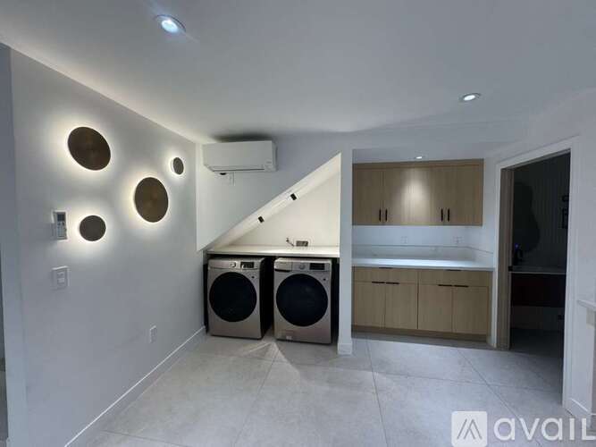 A laundry room with a washer and dryer, a bench, and a wall-mounted air conditioner unit.