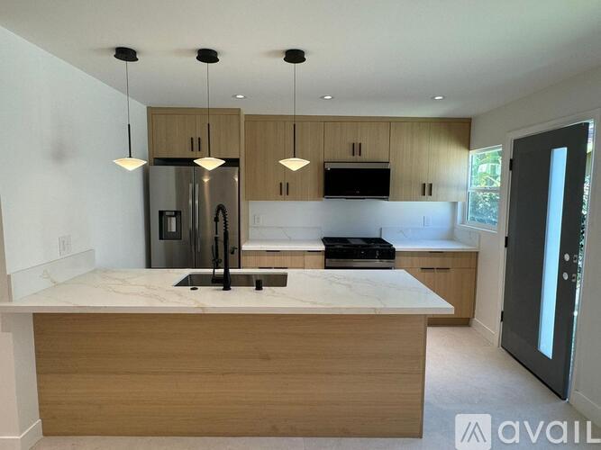 A kitchen with a marble countertop and wooden cabinets.