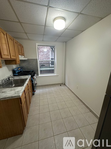 A kitchen with wooden cabinets and a window overlooking a brick building.