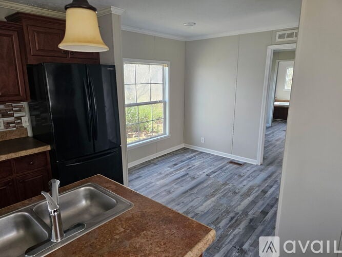 A kitchen with a black refrigerator and a sink.