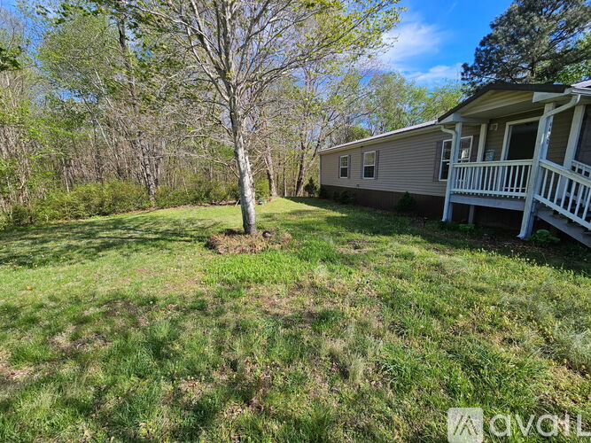 A house with a porch and a tree in the front yard.