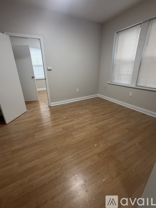 A room with wooden flooring and a window with blinds.