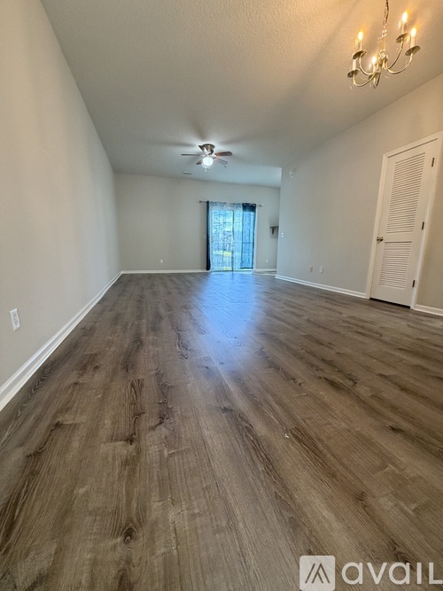 A room with wooden flooring and a chandelier.