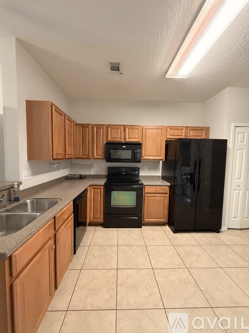 A kitchen with wooden cabinets and black appliances.