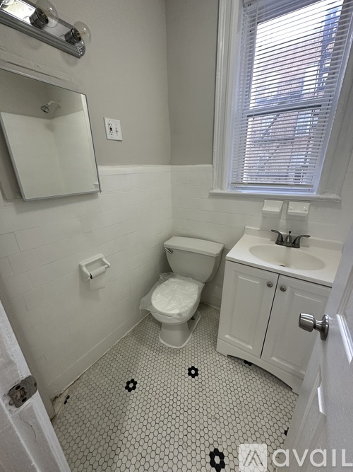 A white bathroom with a toilet, sink, and mirror.