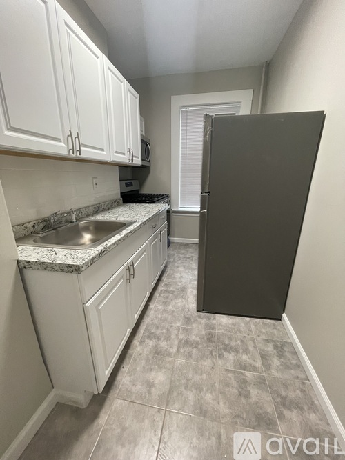 A kitchen with white cabinets and a black refrigerator.