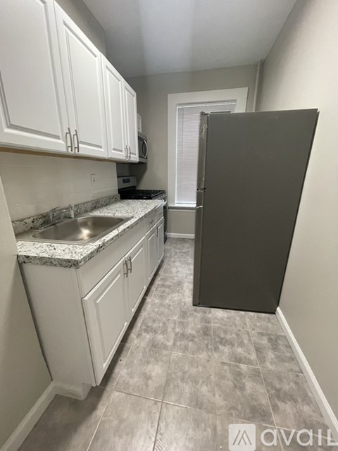 A kitchen with white cabinets and a black refrigerator.