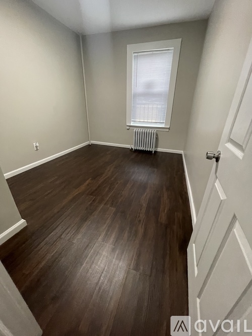 A room with wooden flooring and a window with blinds.