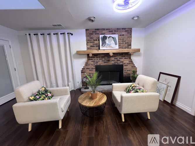A living room with a fireplace and two chairs.