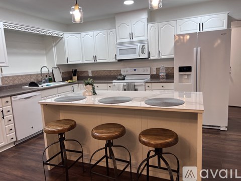 A kitchen with white cabinets and a white refrigerator.