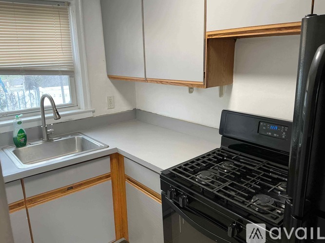 A kitchen with a black stove and a window with blinds.