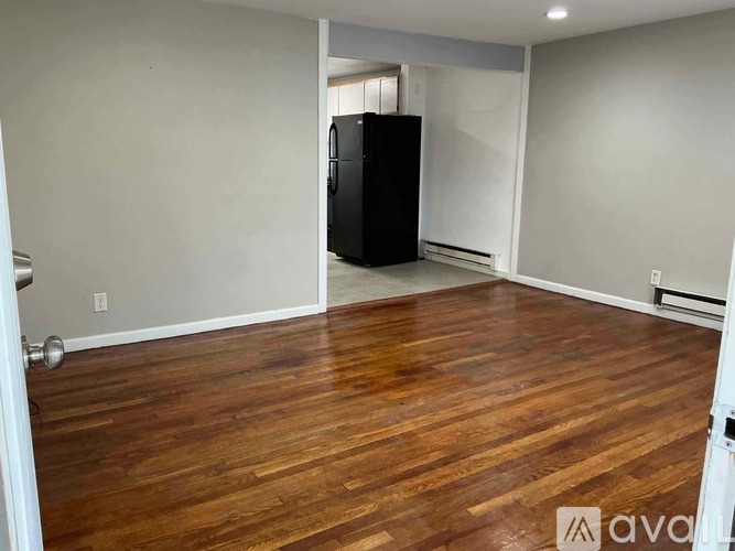 A room with wooden flooring and a black refrigerator.