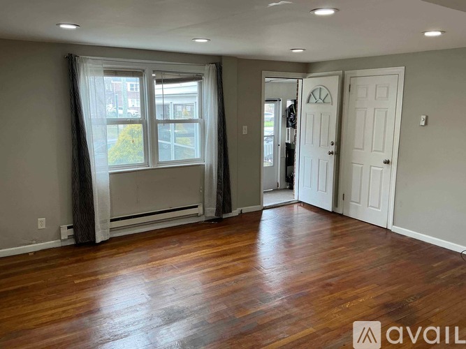 A room with wooden floors and a window with curtains.