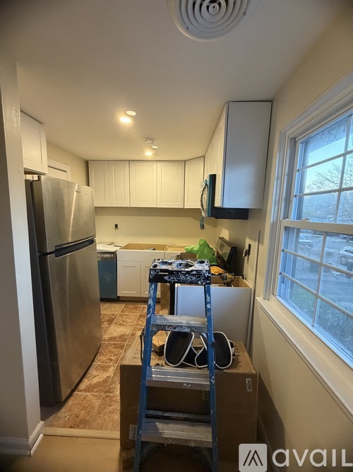 A kitchen with a refrigerator, a window, and a ladder.