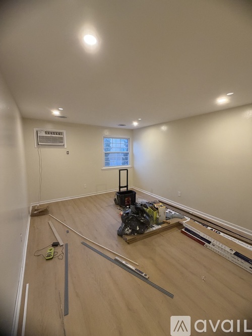 A room with wooden flooring and a window is under construction.