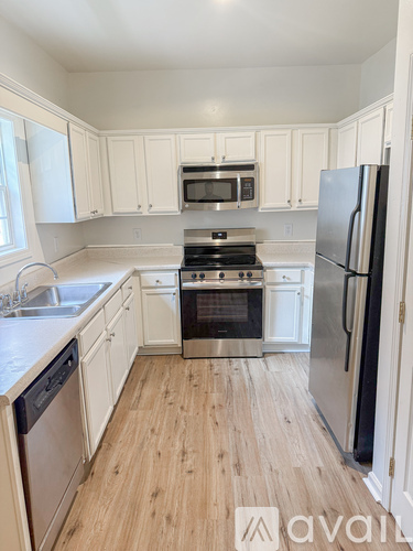 A kitchen with white cabinets and a wooden floor.