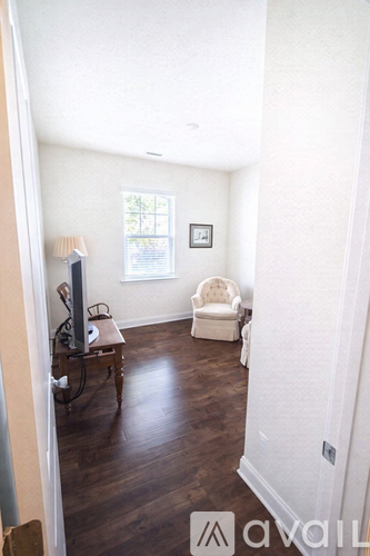 A living room with a white chair and a brown floor.