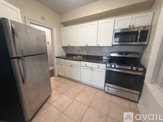 A kitchen with white cabinets and a stainless steel refrigerator.