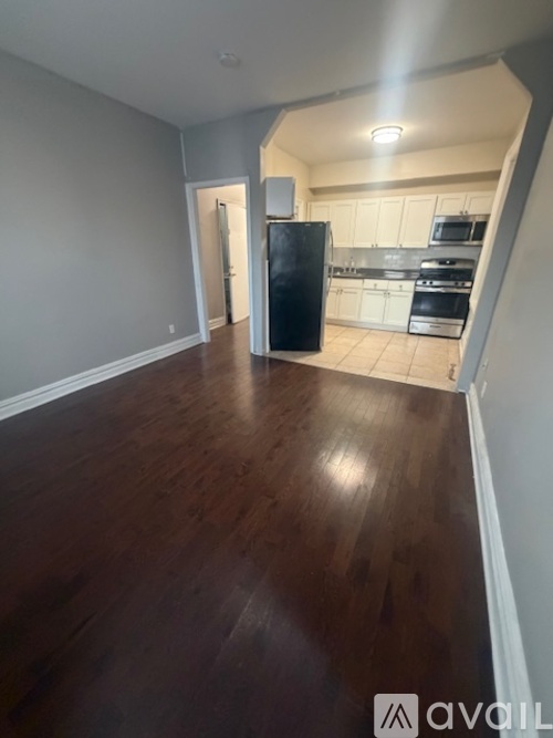 A kitchen with a black fridge and wooden floors.