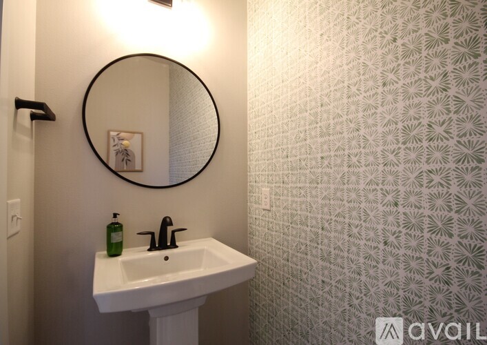 A bathroom with a white sink and a round mirror.