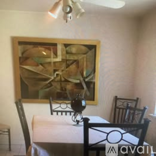 A painting hangs on a wall above a table with chairs.
