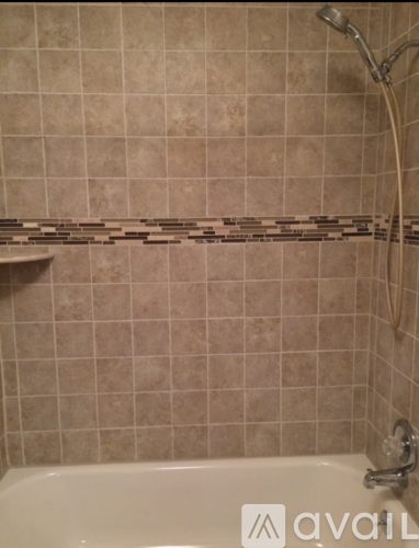 A bathroom with a beige tile wall and a white bathtub.