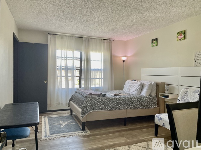 A bedroom with a bed, chair, and window.