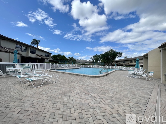 A pool area with chairs and a building in the background.