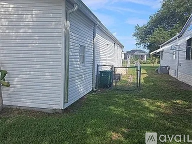 A small white house with a green trash can in front of it.
