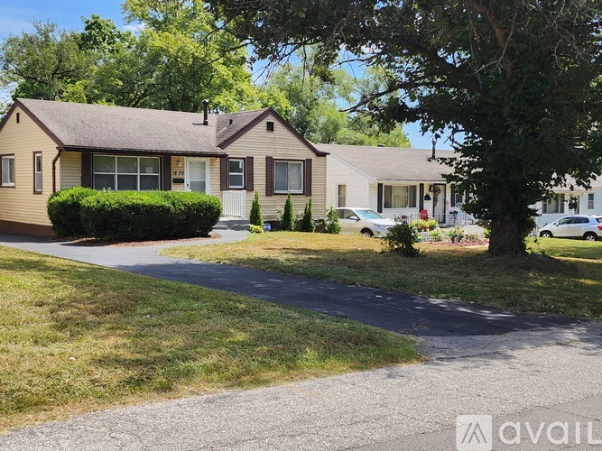 A house with a driveway and a tree in front of it.