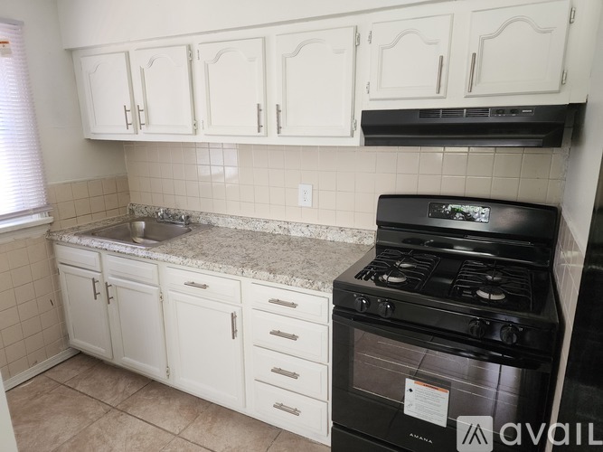 A kitchen with white cabinets and a black stove top oven.