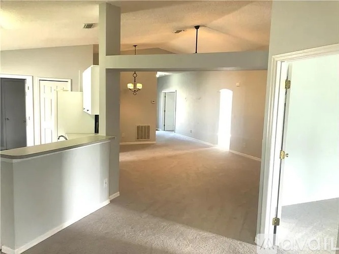 A spacious room with a bar area and a door leading to another room.