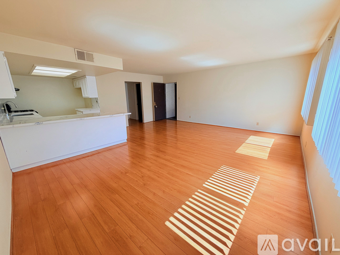 A spacious room with wooden flooring and a striped rug.