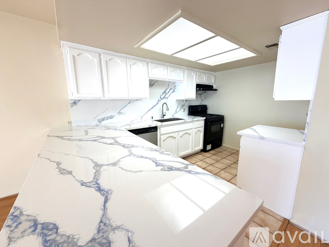 A kitchen with a marble countertop and white cabinets.