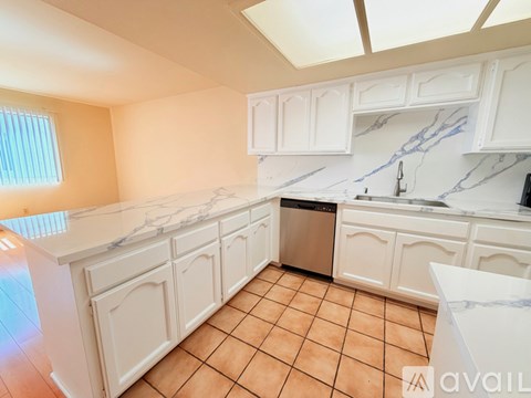 A kitchen with white cabinets and a marble countertop.