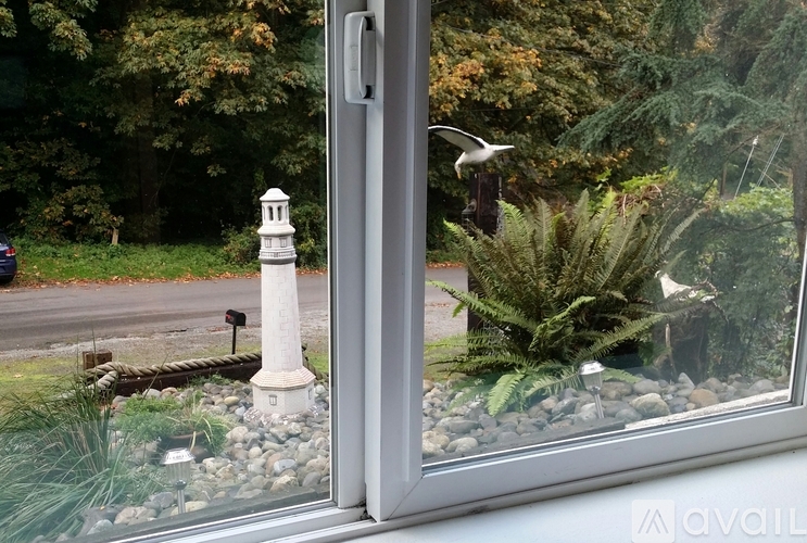A white lighthouse stands in a garden with a glass window.