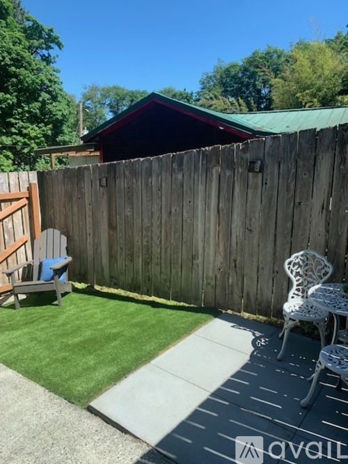 A backyard with a wooden fence, a chair, and a small table.