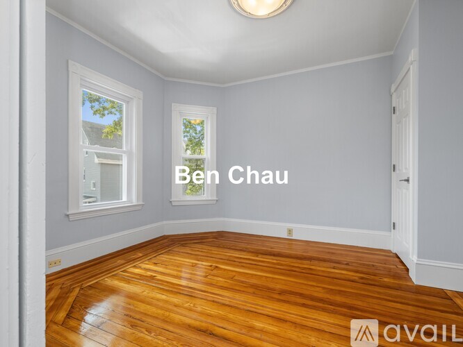 A room with wooden flooring and a window with a view of a building outside.