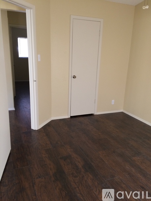 A room with a white door and wooden flooring.