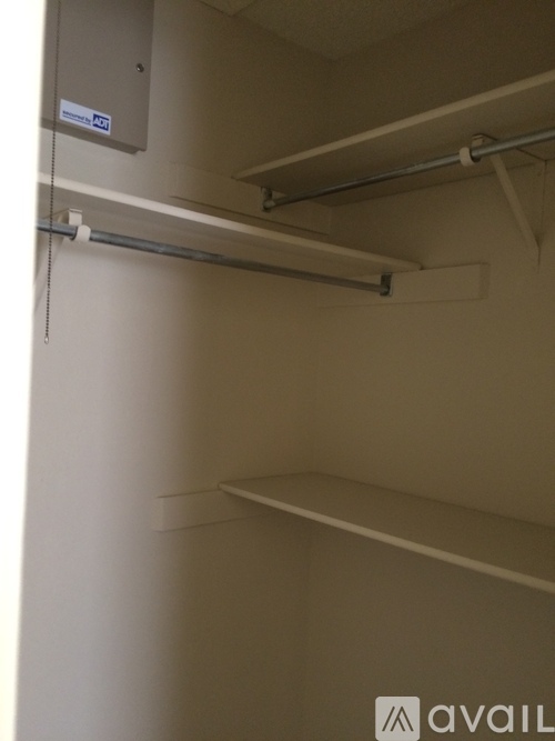 A white wall with a shelf and a metal rod.