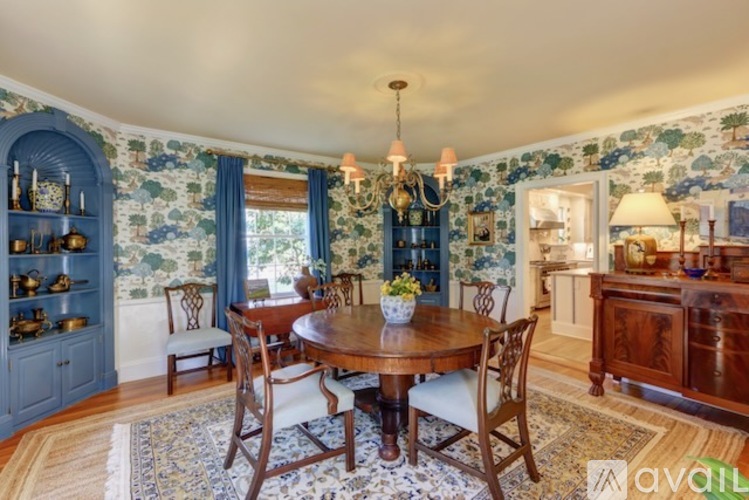 A dining room with a table set for four and a chandelier hanging from the ceiling.