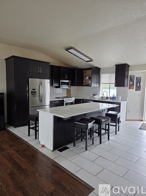 A kitchen with black cabinets and a white island.