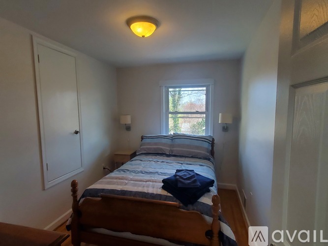 A bedroom with a bed, a window, and a wooden floor.
