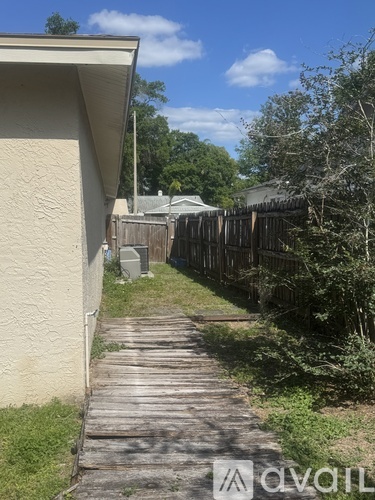 A wooden walkway leads from a house to a fence.