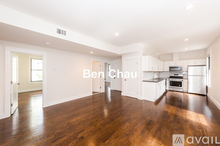A spacious, empty living room with hardwood floors and white walls.