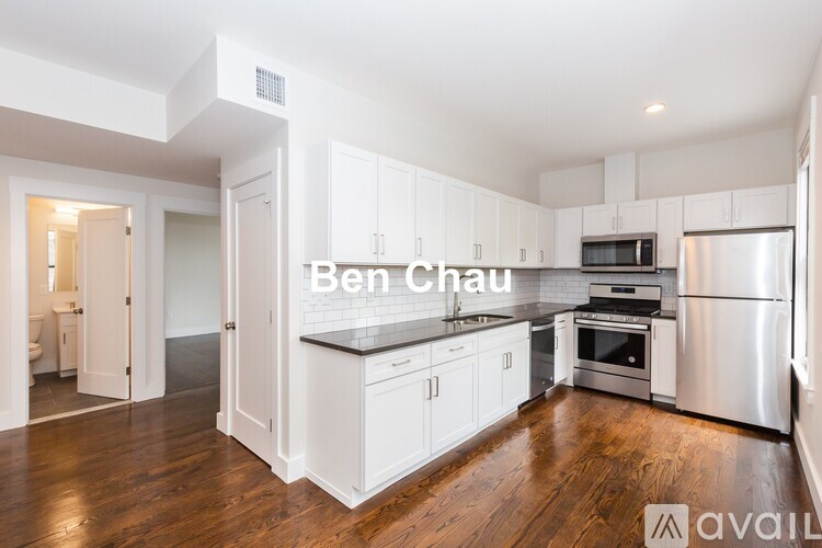 A kitchen with white cabinets and a wooden floor.