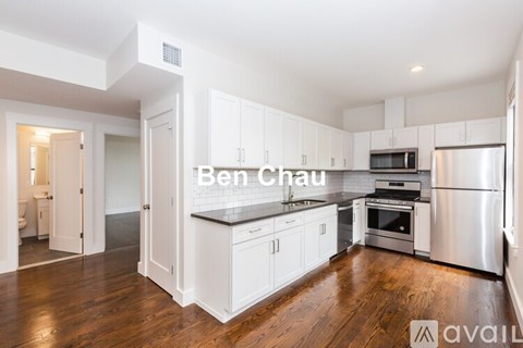 A kitchen with white cabinets and a wooden floor.
