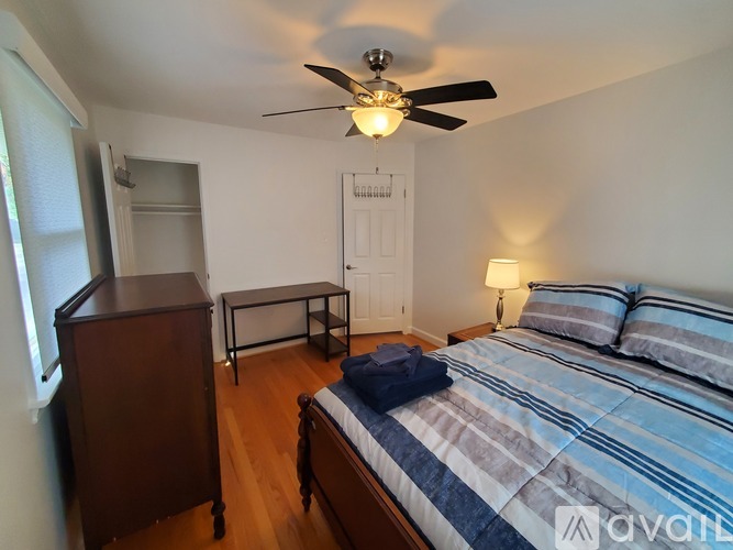A bedroom with a bed, nightstand, and a ceiling fan.