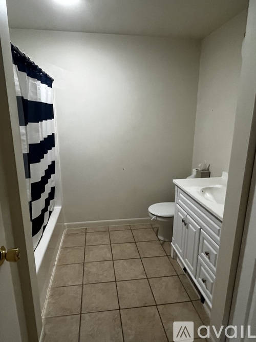 A bathroom with a toilet, sink, and a door with a checkered curtain.